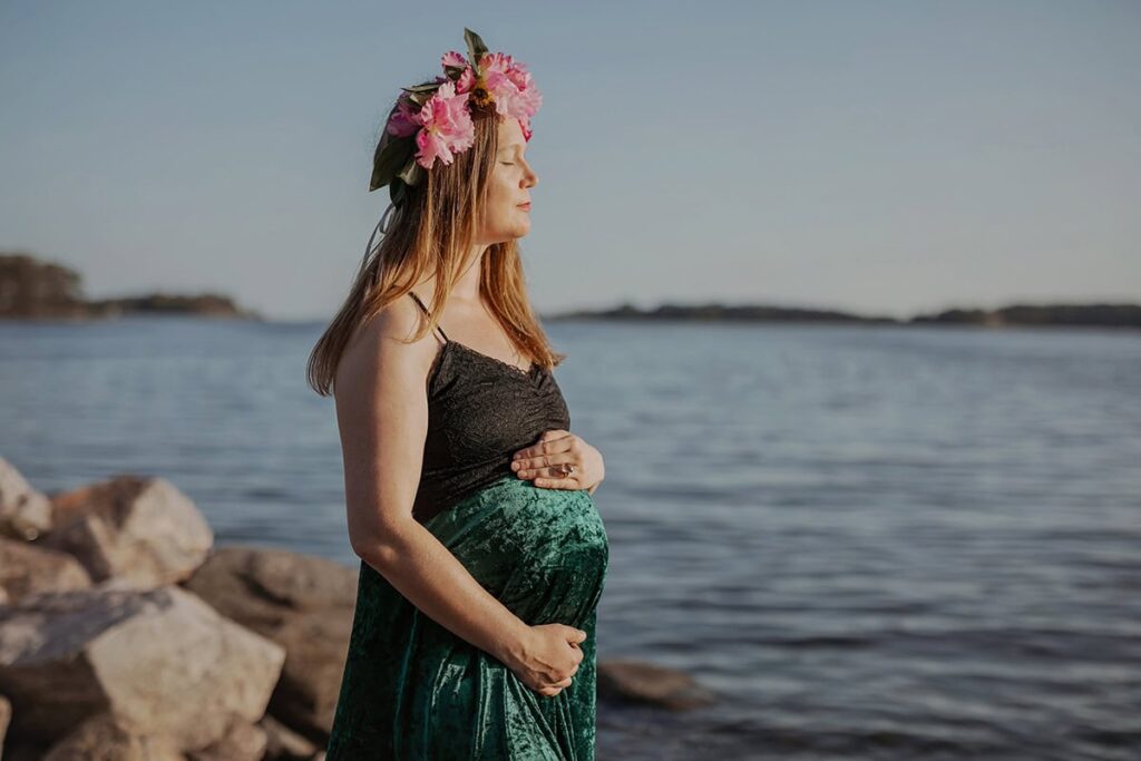 Raskaana oleva nainen nauttii iltauringosta.