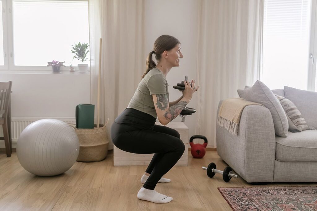 Personal trainer tekee maljakyykky käsipainolla.